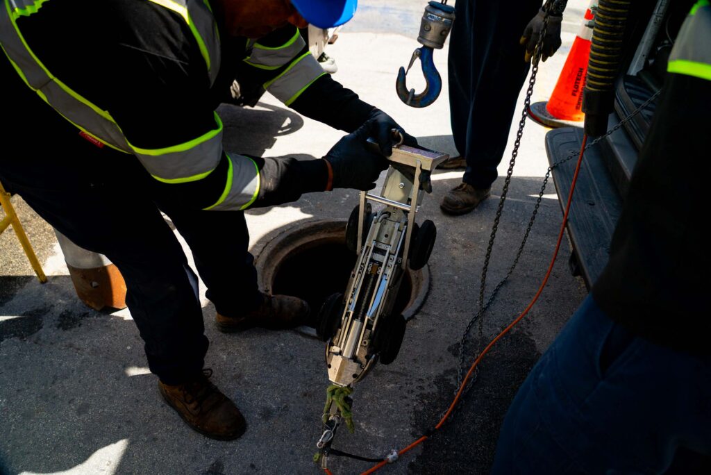 A technician operates a CCTV camera for pipe inspection, showcasing the interior of a pipeline on a monitor screen.