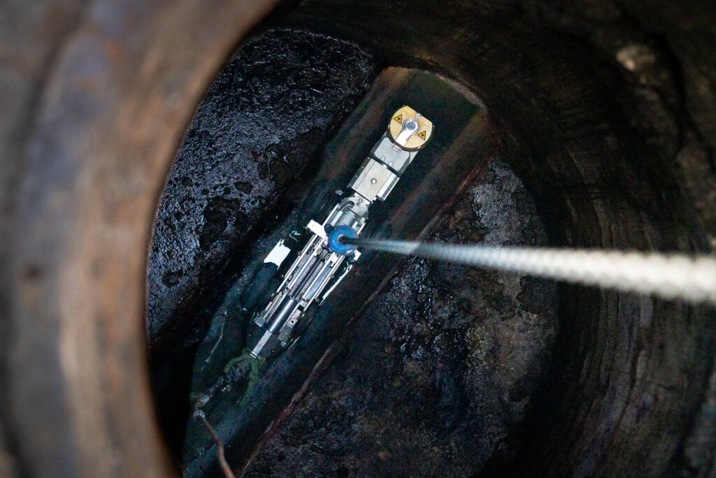 Technician operating CCTV equipment for pipe inspection in an industrial setting, showcasing advanced technology in use.