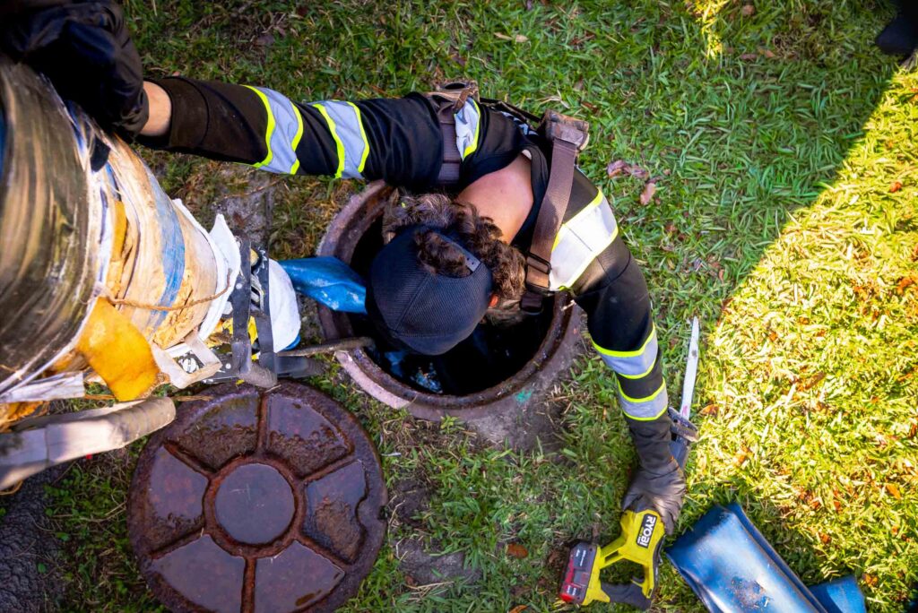 A worker in protective gear installs a CIPP lining inside a large pipe, highlighting trenchless pipe repair technology.