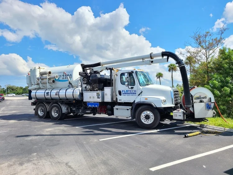 Deep well cleaning equipment setup at a site, featuring hoses and machinery, under a clear blue sky.