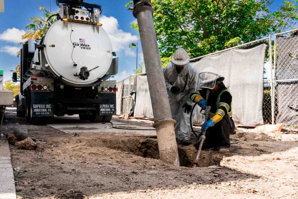 Hydro excavation equipment in operation, showcasing a large vacuum truck with hoses and workers managing the excavation site.
