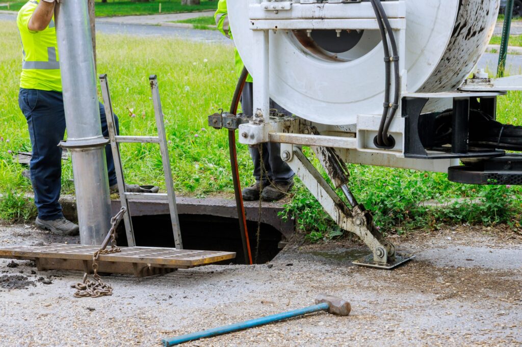 Truck-mounted machine cleaning sewer wells on a town street, illustrating wastewater infrastructure maintenance Florida.