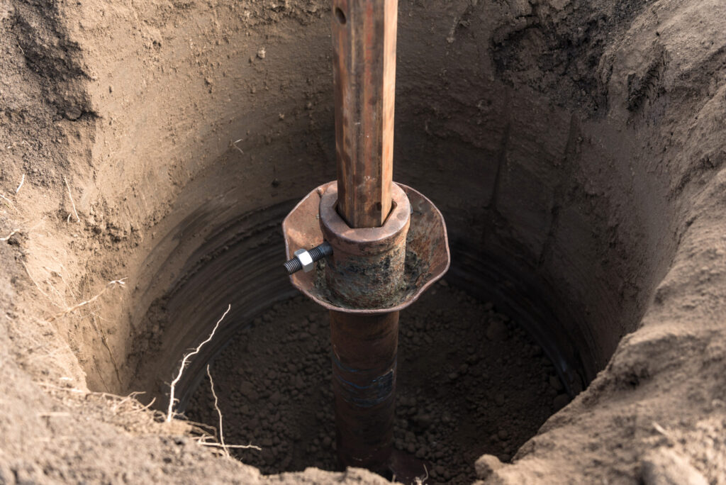 Rustic metal post in a dirt hole, part of wastewater infrastructure maintenance Florida, using a tracer tractor with auger.